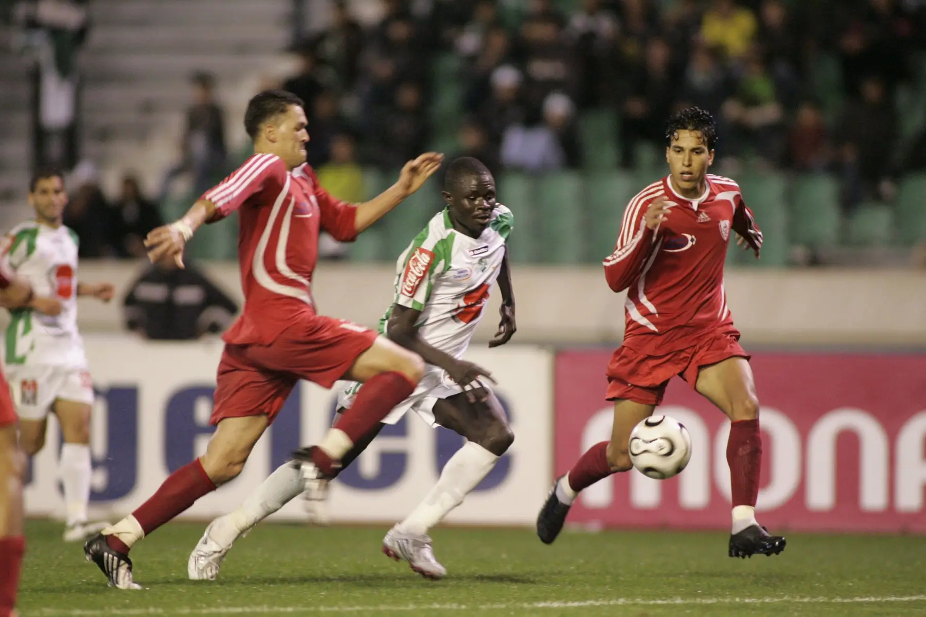 Deux joueurs de l’IZK encadrent un joueur du Raja, le 6 mars 2009. Photo : Mustapha Ennaimi, CC BY 2.0